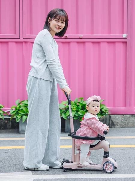 母亲推着宝宝滑板车的温馨街拍写真