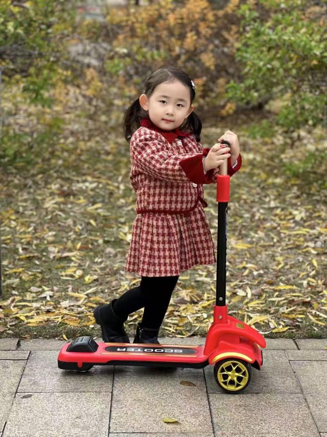 秋日童趣：红裙小女孩骑滑板车写实摄影
